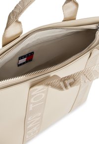 Beige syntetisk shopper taske med dobbelte stofstropper, lynlåslukning og indvendig logoetiket. Har et minimalistisk design og struktureret form.