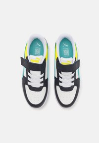 Zwart-witte sportschoenen met een teal en gele ontwerp, voorzien van een klittenbandsluiting, witte veters en een geperforeerde neus voor ventilatie.