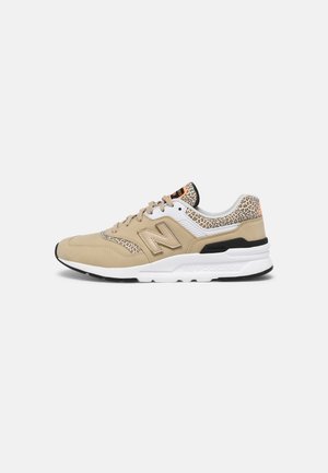 Beige en witte New Balance sneaker met luipaardprint accenten en beige veters, vanaf de zijkant getoond op een witte achtergrond.