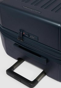 Marineblauer Hartschalenkoffer mit vertikalen Rillen, doppelten Reißverschlüssen, integriertem Zahlenschloss, USB-Anschluss und ausziehbarem Griff.