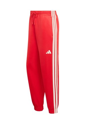 Crvene atletske hlače s bijelim bočnim crtama, elastičnim pojasom s vezicom, sužene na gležnjevima i s logom Adidasa u bijeloj boji na lijevoj nozi.