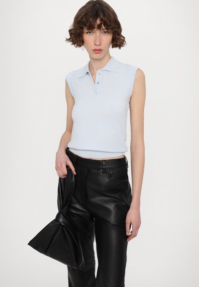 Haut polo sans manches côtelé bleu clair avec un col et trois boutons, associé à un pantalon en cuir noir taille haute.