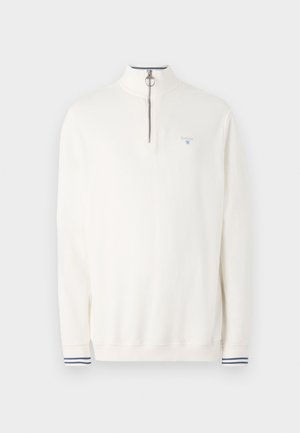 Valge poolpikkade varrukatega sviiter, millel on neljandik tõmblukk, hõbedased detailid ja väike sinine logo. Omab triibulisi mansette, kus on tumesinine ja valge muster.