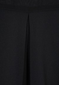 Černá tkanina s vertikálním přešitím, měkkou texturou a hladkým povrchem, navržená pro elegantní a minimalistický vzhled.