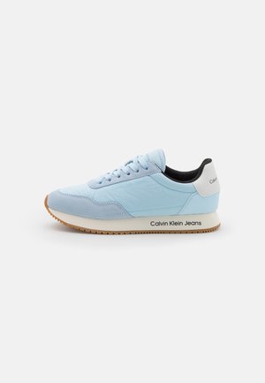 Hellblauer Calvin Klein Jeans Sneaker mit Schnürung vorne, weißem Fersenriemen, schwarzem Innenfutter und Gummisohle auf weißem Hintergrund.