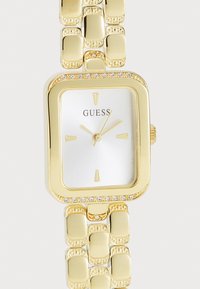 Gold-tone watch with a rectangular case, white textured dial, gold hour markers, and a band featuring polished rectangular links. Accented by crystals.