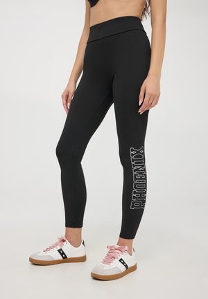 Leggings neri con un alto punto vita, caratterizzati dalla parola "PHOENIX" in grassetto bianco sulla gamba sinistra. Tessuto morbido e elastico.