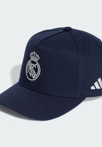Casquette de baseball bleu marine, en matériau coton, équipée d'un logo Real Madrid brodé en relief et de trois rayures blanches sur le côté. Design structuré, visière courbée.