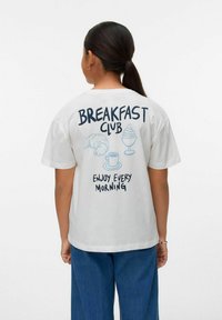 Camiseta de algodón blanca con el texto "BREAKFAST CLUB", ilustraciones de un croissant, helado y una taza de café. Mangas cortas y corte relajado.