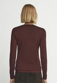 Mörkröd långärmad tröja med rund halsringning. Slät textur, kroppsnära design och ribbade ärmslut. Ren, minimalistisk stil utan märkbara mönster.