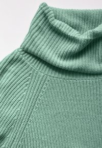 Ljus myntgrön stickad tröja med ribbad polokrage och texturerad sömnad. Tyget är mjukt med vertikala ribbmönster.