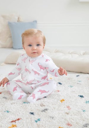 Hvide babypyjamas med pink dinosaur mønster, lange ærmer, lynlås foran og foddesign. Blødt stof på tekstureret tæppe.
