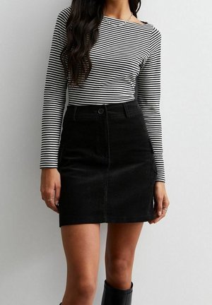 Black corduroy mini skirt with front button closure, paired with a fitted black and white striped long-sleeve top. Smooth texture, casual design.