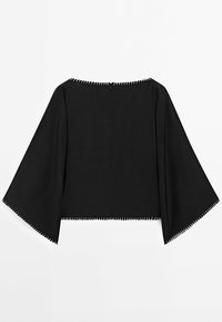 Haut noir court en tissu texturé avec des manches larges et ouvertes, et une couture blanche contrastante le long de l'ourlet et de l'encolure.