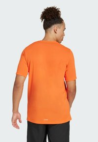 Men's short-sleeve orange t-shirt made from smooth fabric with a round neckline and a slightly curved hem. Visible logo on the back.