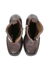 Botas de cuero marrón hasta el tobillo con una textura suave, cremalleras laterales y un diseño de punta redondeada. El interior cuenta con un suave forro en tono beige.