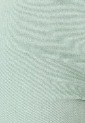 Light green fabric with a smooth, textured finish and diagonal weave pattern, showcasing subtle sheen and softness.