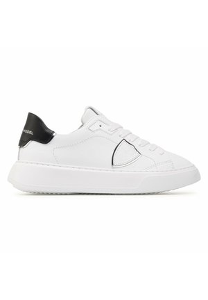 Sneaker bianche in pelle con forma arrotondata, accentuate da un tacco nero e suola in gomma texturizzata; presentano cuciture minime e un design elegante.