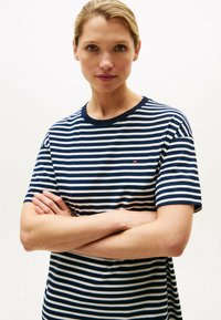 Granatowa i biała w paski koszulka z okrągłym dekoltem i krótkimi rękawami. Posiada małe logo na piersi. Wykonana z miękkiego materiału, o luźnym kroju.