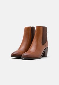 Lette ankle boots i en lys brun farge med en jevn finish. Har elastiske sidepaneler og en stablet hæl for ekstra høyde.