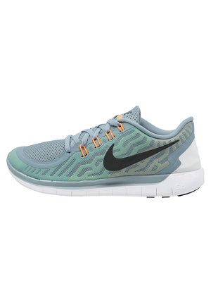 Chaussure de course Nike bleu clair et vert avec un swoosh noir, des œillets orange, une tige en mesh respirant et une semelle blanche flexible.
