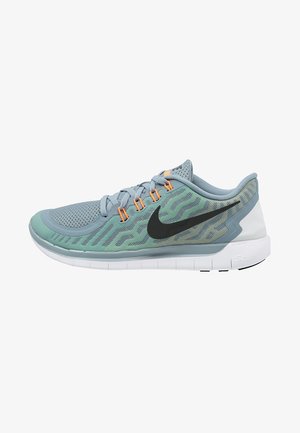 Chaussure de course Nike bleu clair et vert avec un swoosh noir, des œillets orange, une tige en mesh respirant et une semelle blanche flexible.