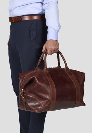 Brown leather duffel bag with smooth texture, dual handles, and contrasting leather accents; features a zip closure and visible stitching details.