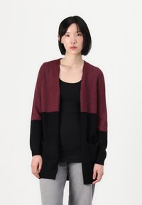 Cárdigan de punto burdeos y negro con mangas largas, frente abierto, dos bolsillos y una textura suave. Corte casual, diseño en capas.