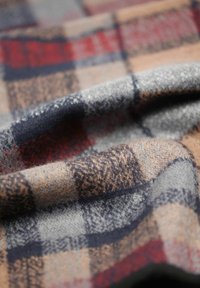Wollstoff mit einem karierten Muster in Grau, Beige, Rot und Marineblau. Weiche Textur mit sichtbaren Fasern.