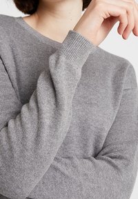 Gray sweater made of soft knit material, featuring a classic round neckline and ribbed cuffs. Fitted silhouette with a smooth texture.