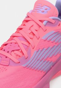 Klarrosa och lavendellila New Balance-sneakers med strukturerad sidodesign och korsade snören, med närbilder av både ovansidan och sidan.