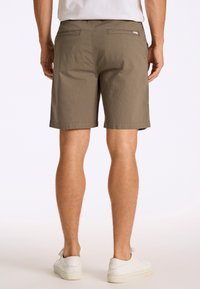 Pantaloni corti verde oliva realizzati in tessuto leggero, con un design semplice, tasche frontali e due tasche posteriori, con una vestibilità dritta.