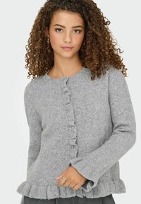 Gilet gris en laine douce avec un ourlet volant, un col rond et une fermeture à boutons. Dispose de manches longues avec des poignets volants.