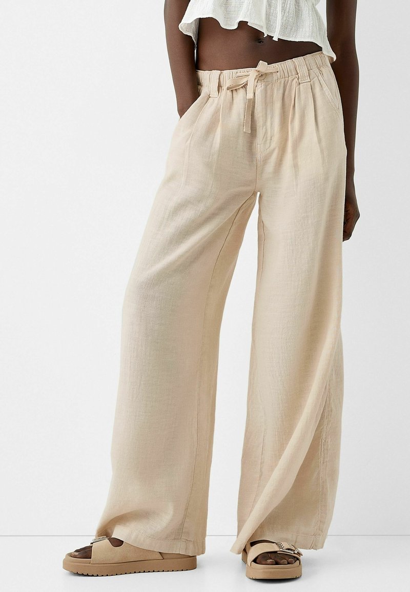 Beige wijde pantalon gemaakt van lichtgewicht stof met een getextureerde afwerking. Voorzien van een elastische tailleband en een trekkoord, ontworpen voor comfort.