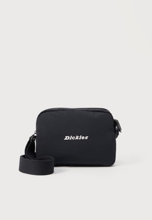 Sort rektangulær skuldertaske med justerbar rem og hvidt "Dickies"-logo centreret på forsiden mod en ensfarvet baggrund.