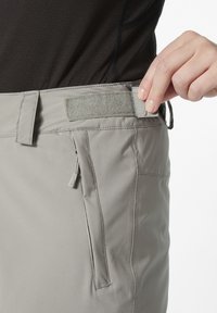 Graue, leichte Hosen mit einem Klettverschlussbund, einer seitlichen Reißverschlusstasche und einem glatten Stoff mit einem dezenten Schimmer.