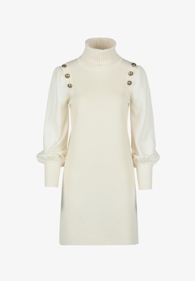 Robe couleur crème à col roulé avec texture côtelée, manches bouffantes et trois accents de boutons dorés sur les épaules. Bustier ajusté avec un bas décontracté.
