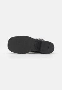 Suela negra de bota con punta cuadrada, tacón bajo, costuras visibles y el nombre de la marca "Steve Madden" grabado en el mediopie.
