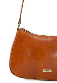 Braune Lederhandtasche mit glatter Textur, geschwungener Form, einem Reißverschluss in Goldoptik und einer kleinen Metall-Logo-Plakette. Verstellbarer Schultergurt.