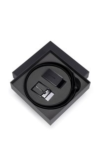 Ceinture en cuir noir présentée dans une boîte carrée noire, avec une boucle noire texturée et un accent en métal argenté. Comprend une pièce de boucle supplémentaire.