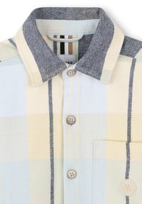 Lichtblauw en geel geruit overhemd met een denimachtige kraag, voorzien van een knoopsluiting aan de voorkant en een enkele borstzak. Opvallende contrasterende strepen.