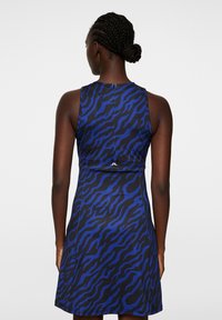 Sukienka bez rękawów w kolorze niebieskim z czarnym wzorem zebry. Gładki materiał z dopasowanym krojem; posiada zamek błyskawiczny z tyłu oraz szczegół logo w talii.