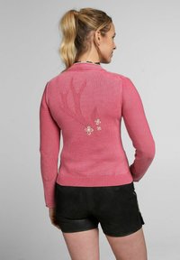 Rosa Langarmpulli mit floralem Stickereidetail und strukturierten Ellenbogen-Patches. Gerippter Saum und Bündchen mit figurbetonter Silhouette.
