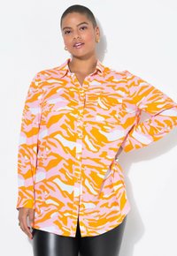 Chemise à boutons à imprimé animal orange et rose, avec un col et des manches longues, dotée d'une poche poitrine et d'un ourlet droit.
