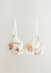 Soutien-gorge en dentelle florale blanche avec motifs de feuilles roses et vertes, bretelles fines réglables et armatures, posé à plat sur un fond clair.