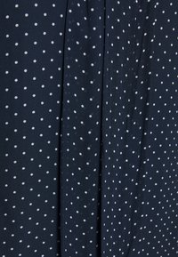 Námořnická látka s bílými puntíky, s hladkým povrchem. Design zahrnuje drapérie pro zvýšení hloubky.