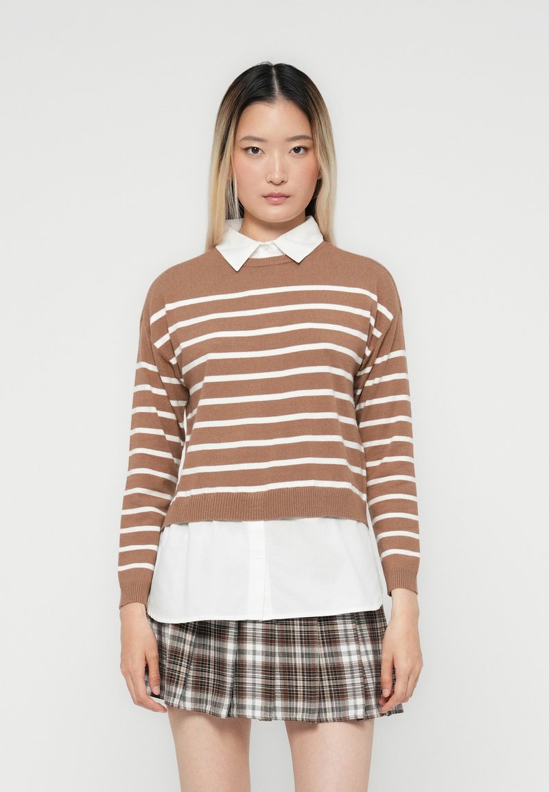 Brown and white striped sweater with a round neckline, layered over a white collared shirt, paired with a plaid pleated skirt.