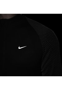 Schwarzes Sportoberteil mit hohem Kragen und Reißverschluss, das über strukturierte schwarze Streifen auf einer Schulter und ein weißes Nike-Logo auf der Brust verfügt.
