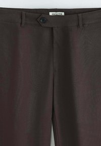 Pantalon marron foncé en tissu lisse, avec une fermeture à bouton et une ceinture simple. Étiquette portant la mention "FRILIVIN."