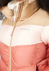 Kurtka puchowa z beżową górną częścią, jasnoróżowym środkowym paskiem i koralową dolną częścią; miękki materiał z zamkiem błyskawicznym.